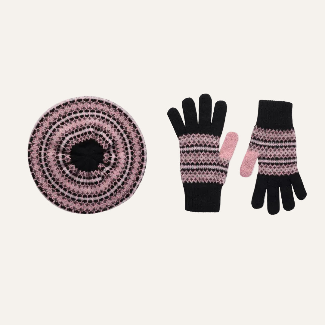 A knit winter accessory gift set on a white background, including a round matching lambswool beret hat and a pair of matching gloves. The hat and gloves feature a black base with pink and white Fair Isle style stripes, and the fingertips of the gloves are solid pink.