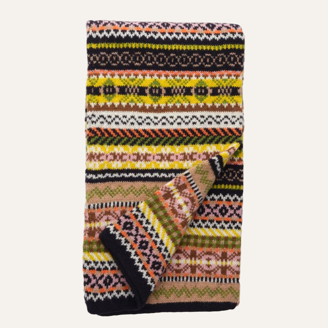 Knit scarf featuring a colorful Fair Isle pattern, featuring stripes of yellow, green, orange, black, and beige on a white background.