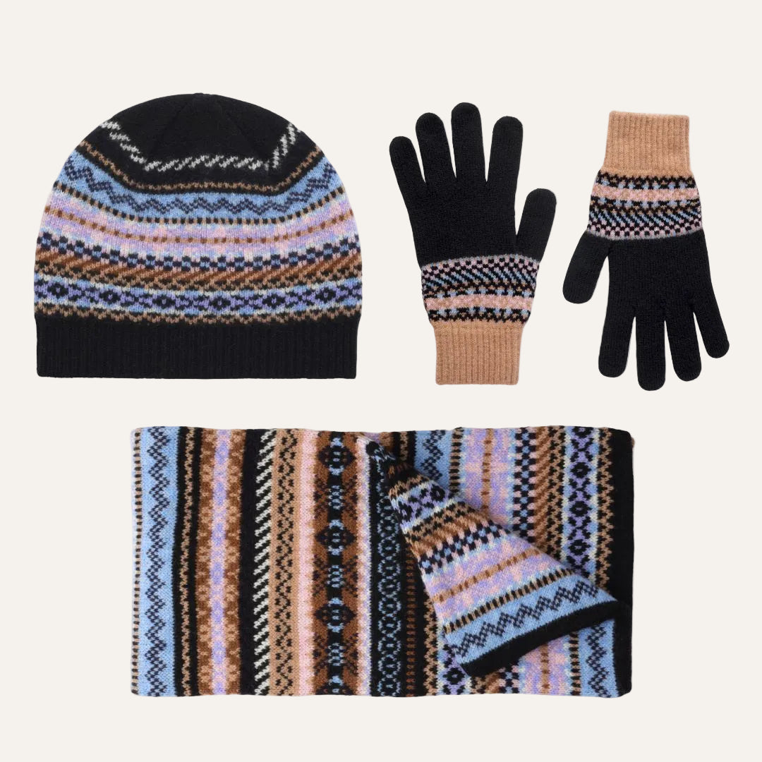 Lambswool winter accessory set on a white background, including a beanie, gloves, and a scarf. The items feature a multicolor Fair Isle pattern with black, light blue, peach, and brown stripes.