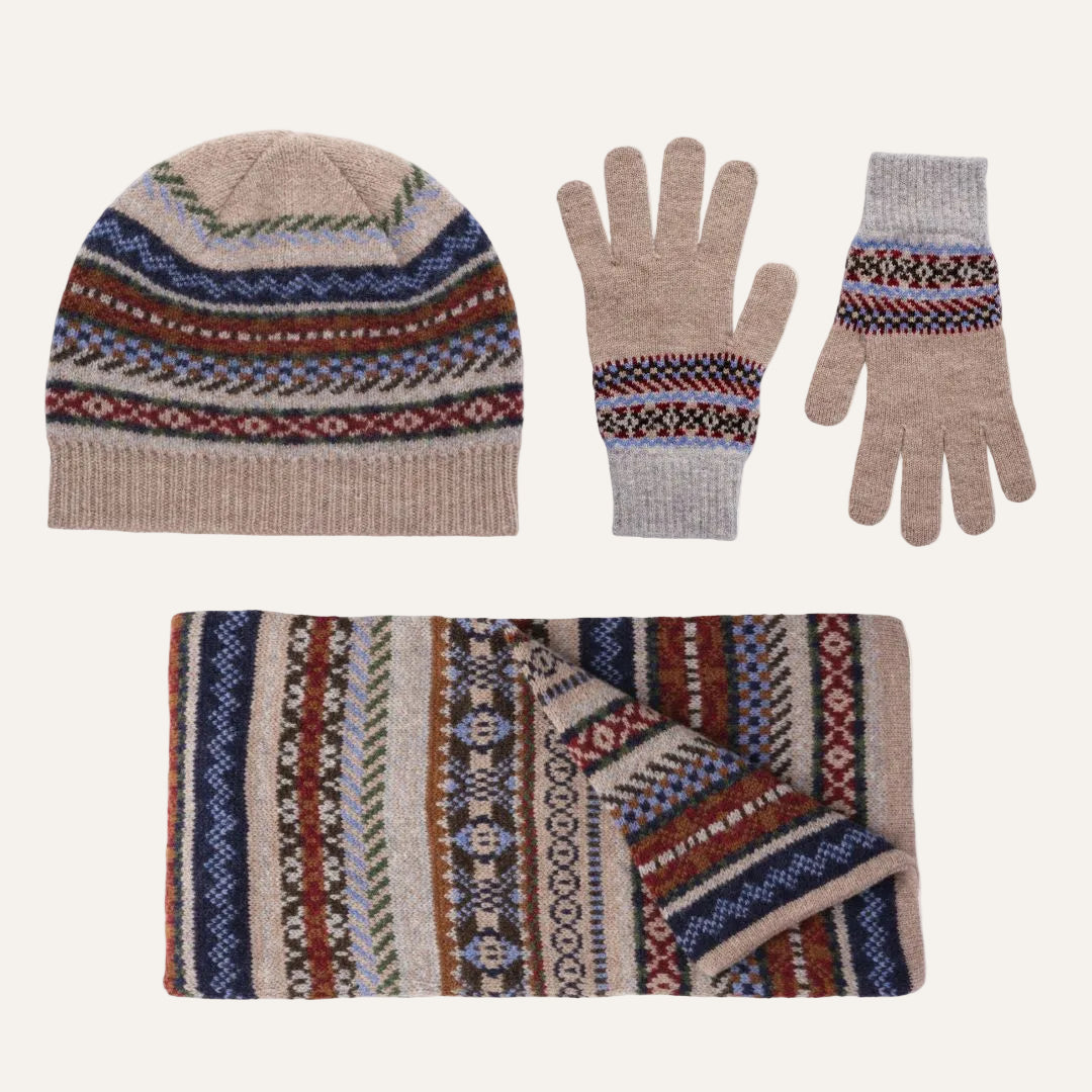Lambswool winter accessory set on a white background, including a beanie, gloves, and a scarf. The items feature a beige base with multicolor Fair Isle patterns in blue, red, brown, and green.