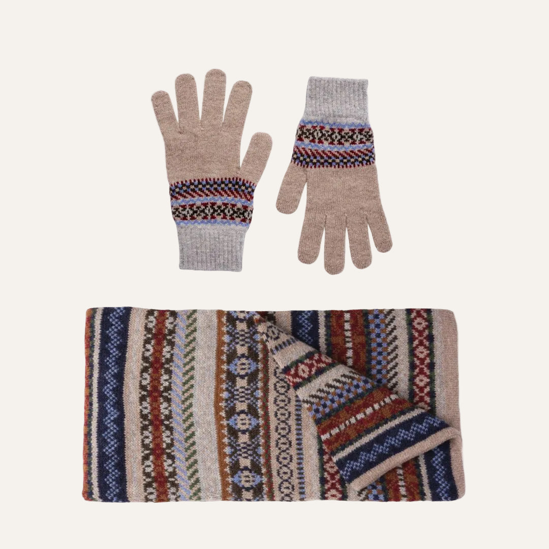 Lambswool knit winter accessory set on a white background, featuring a pair of beige gloves with multicolor Fair Isle patterns and a matching folded scarf with a complex geometric pattern in beige, brown, red, blue, and green.
