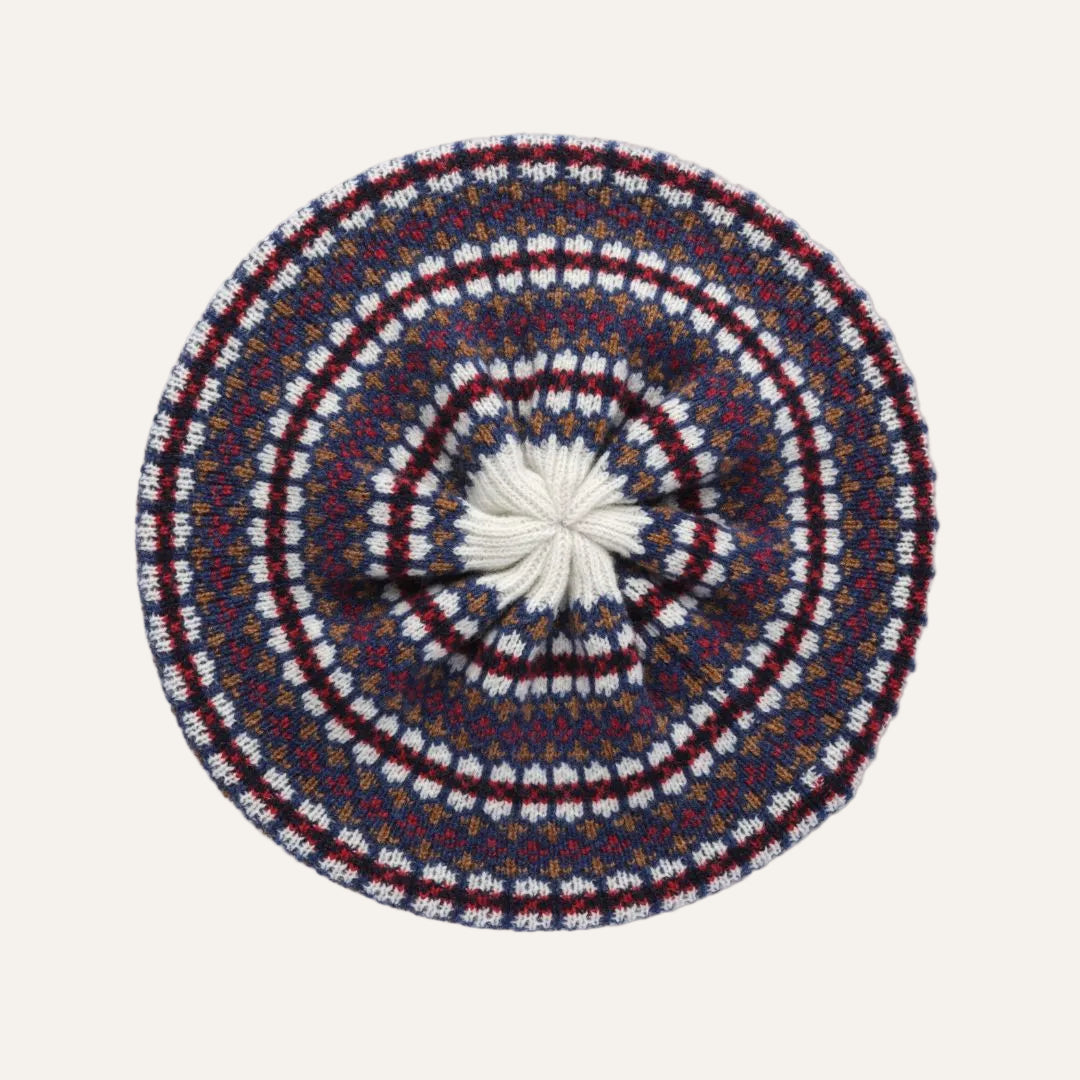 A round knit beret hat with concentric circular patterns in blue, burgundy red, and white.