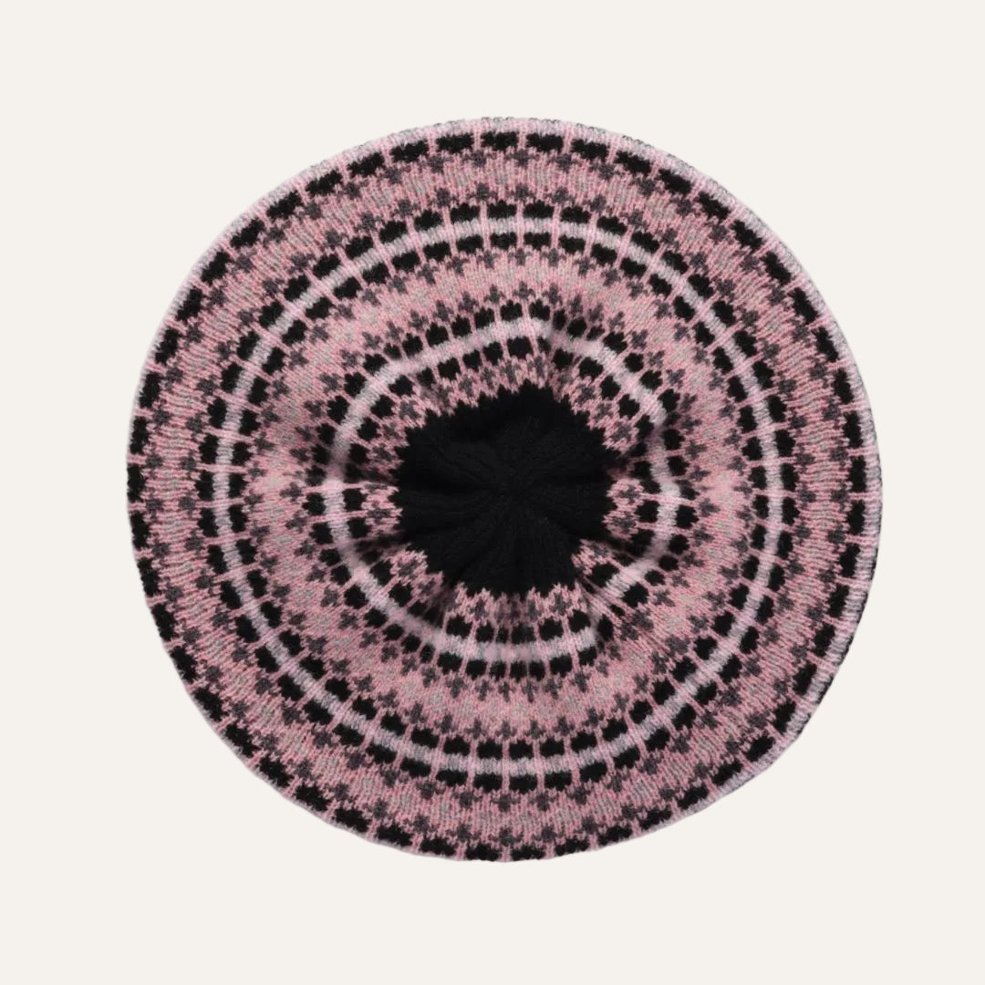 A round knit beret hat featuring a concentric circular pattern in pink, black, and white, with a solid black center.