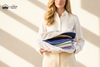 Woman holding folded cashmere garments in open cotton storage bag